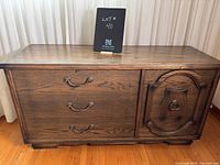 Full view of vintage wooden chest showing three drawers on left and decorative panel door on the right.