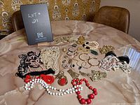 Photo of assorted costume jewelry laid out on a marble table including necklaces, bracelets, earrings, and brooches.