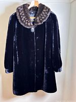 Front view of black faux fur coat with patterned faux fur collar and button closure