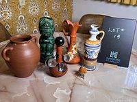 Photo showing six vintage souvenir ceramic and pottery items on tabletop with various decorative motifs and shapes