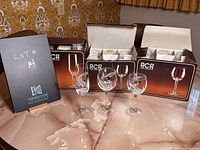 Three sets of crystal glasses in original boxes behind four individual glasses displayed in front.