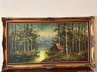 Full view of vintage framed landscape painting on canvas. Features a forest lake scene with a cabin, swans, and misty mountains in the background.