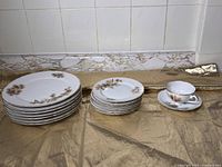 White china plates and cup with pine tree pattern arranged on gold cloth