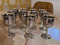 Set of 11 metal goblets displayed on a table, showing all goblets together.