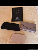 Photo showing all three vintage clutch purses on a beige surface: black mesh clutch, taupe envelope clutch, white mesh clasp purse.