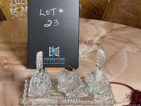Full view of the glass perfume set with black lot sign in the background.