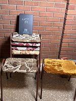 Photo showing five vintage stacking stools stacked and one separate showcasing the different upholstery patterns and metal frames.