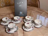 Photo showing 6 vintage Japanese tea cups with matching saucers on a marble surface, arranged in two groups of three with different floral patterns.