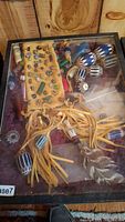 Full overview of items in case showing leather bag with beadwork, feathers, and multiple beads on fringe and inside case