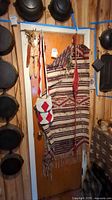 Full view of the woven blanket, beaded bags, woven belt, and corn husk hanging on a door