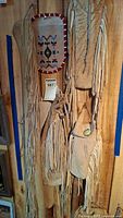 Four buckskin bags hanging on wooden wall, showing styles, fringes, and beadwork on flap of one bag.