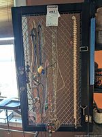 Full view of multiple costume jewelry necklaces hanging on wire mesh display, showing variety in bead styles and metal chains.