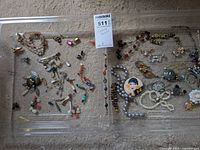 Two trays displaying a large collection of costume jewelry items including earrings, necklaces, bracelets and pins arranged on carpet background.