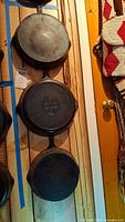 Three cast iron fry pans stacked vertically showing underside and relative sizes
