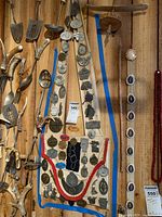 Canvas bag covered with various collectible metal pins from Indigenous American Tribe Festivals, shown hanging on a wooden wall with other items around.