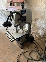 Side view of the complete Delta Shopmaster electric band saw showing the motor, work table, and blade area with flexible lamp attached.