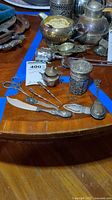 Full view of the sterling silver tea accessory set showing various items on a wooden surface including tongs, scissors, jar, and spreader.