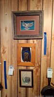 Three framed animal art prints hung on a wooden wall panel, one above the other, numbered 590 and 591 on tags below