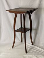 Full view of the tall wooden stand with square tabletop and lower shelf, showing the structure and finish.