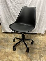 Black rolling swivel chair with molded ergonomic seat and five caster wheels shown from angled side.