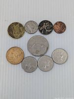 Top-down photo of eight Canadian coins in various denominations and wear levels laid on white surface.