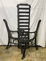 Full view of cast iron bench frames including two side frames and one backrest frame stacked behind