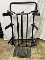 Front view of metal utility cart with arms for toolbox attachment and a foldable platform.