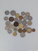 Photo showing an assortment of various international coins laid out on a white background, showing a mix of colors and conditions