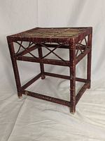 Full view of square burgundy wicker table showing woven top surface and wicker wrapped frame.