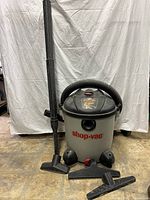 Front view of Shop Vac Plus wet/dry vacuum with hose and extension piece attached, showing the overall design and size.