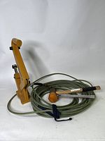 Stanley Bostitch flooring nailer laid flat with green coiled pneumatic compressor hose and wooden handle rubber mallet hammer beside it.