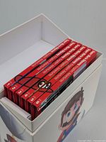 Photo of six Super Mario Odyssey travel companion books in original white box with Mario and Cappy images. Books numbered 1 to 6 with red spines.