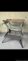 Full view of the folding adjustable work table showing metal base, wooden top, and side support.