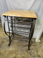 Front angle view of the wood top and metal wine rack showing the 3 shelves and scrolled legs