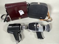 Bell & Howell and Bauer 8mm film cameras side by side with their respective carrying cases on a white background.