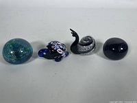 Photo showing all four pieces together: blue orb with internal swirls, blue turtle, black and white snail, and cobalt blue orb