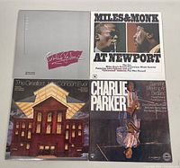 Four vintage jazz record albums displayed face up on a floor, showing their front covers: Charlie Parker album, Miles & Monk At Newport, and others.