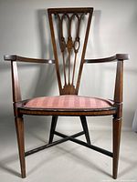 Full front view of the English Art Nouveau mahogany armchair with upholstered pink striped seat showing overall shape and design.