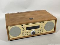 Angled front view showing walnut cabinet, front panel, speaker grilles and control layout