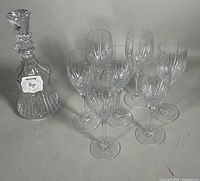 Decanter with stopper and eight matching wine glasses grouped together, showcasing the entire set