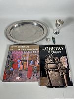 Lot overview showing two paperback Judaica history books, silver Kiddush cup, small mezuzah, two silver miniature items, and silver serving tray