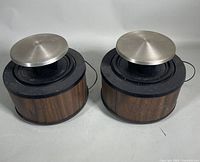 Pair of vintage stereo speakers showing front and top angled view, wood veneer cabinets with large metal domes on top.