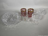 Photo of the full lot showing the Waterford crystal bowl, Waterford glasses, and the pair of cranberry gold gilded glasses