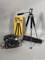 Photo showing the ZEISS IKON Contaflex camera in brown leather case with two tripods, one King Cine Tripod 10 motion with box, and one smaller black tripod with black case.