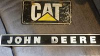 Photo showing both signs: John Deere long horizontal sign and smaller rectangular CAT sign