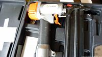 Paslode Lite Line air nailer showing the gun with metal and plastic components, black grip and orange trigger and accents inside the case.
