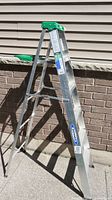 Side view of Werner aluminum step ladder showing overall structure and green plastic top.