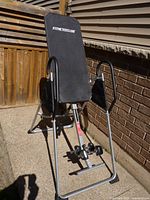 Full view of the inversion therapy table showing padded backrest with FitnessClub logo, steel frame and handles