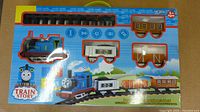 Front view of the sealed 14-piece Kids Train Set in colorful box packaging showing blue engine, train cars, and black track pieces with 'Train Story' branding.