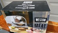 Photo of the Weston meat slicer in its original box with product image and branding.